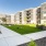 Shady courtyard with walking paths, lush green lawn, and cornhole boards