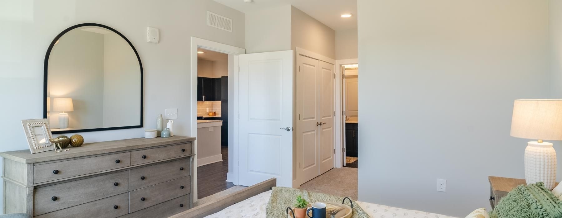 Model bedroom at our senior living community in Buford, GA, featuring white bedspread and a view of the closet.