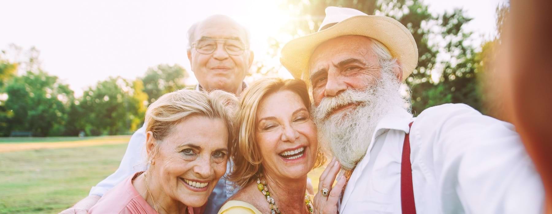 Residents standing outside and taking a selfie at Outlook Gwinnett 55 and older apartments, featuring warm sunlight.